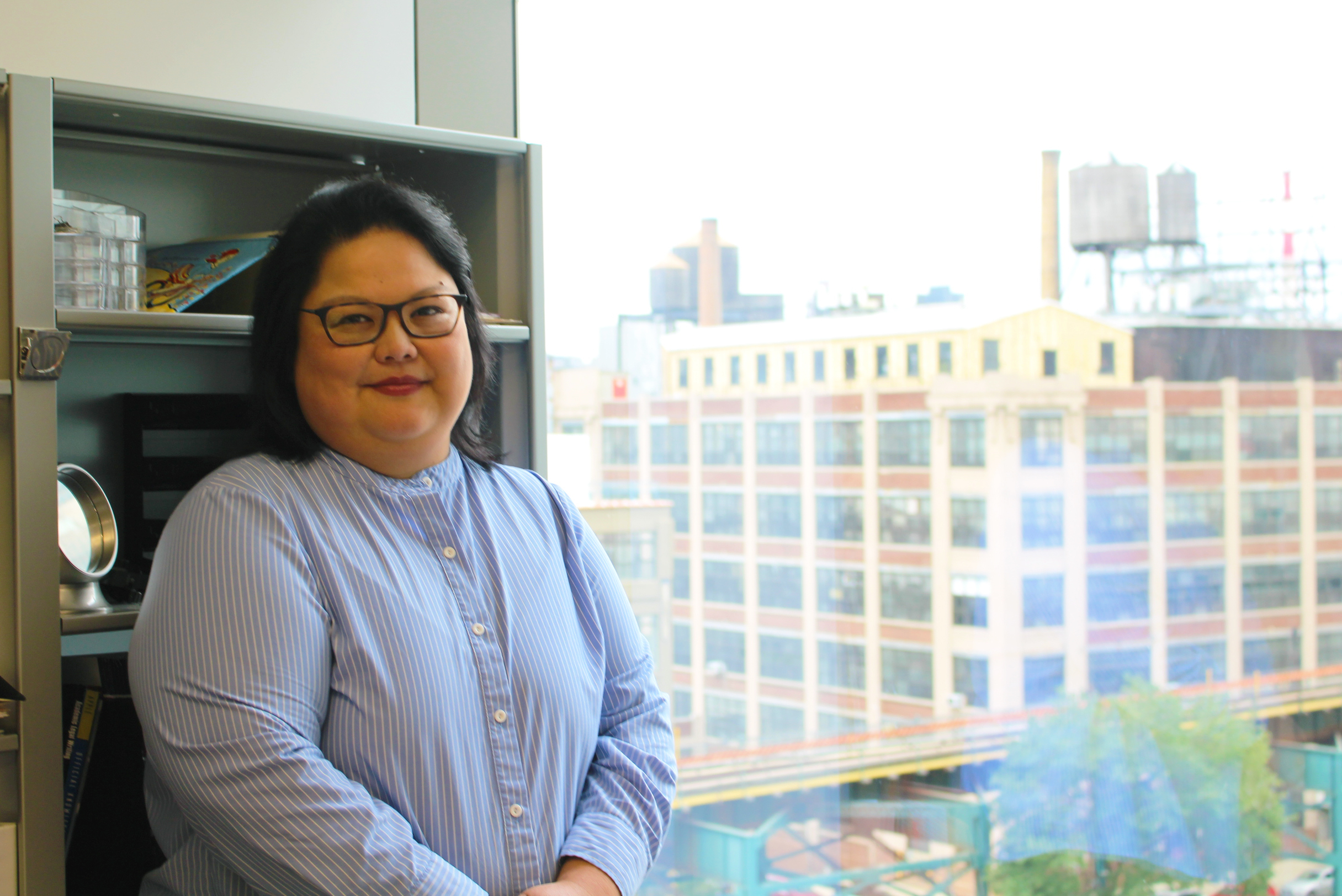 Professor Raquel J. Gabriel in front of a window view of Long Island City