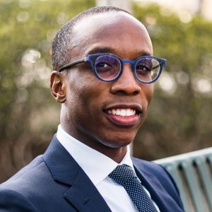 Scott Kennedy '20 smiles while wearing blue spectacles that match his blue suit and necktie in this portrait