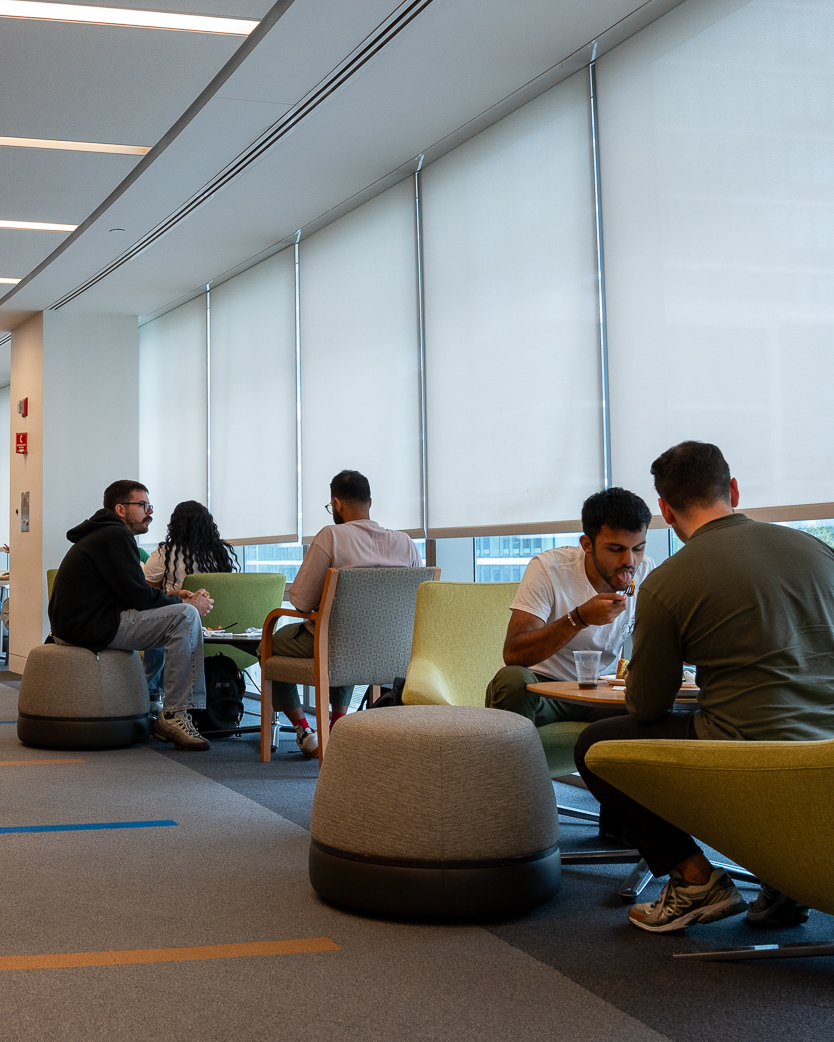 Students sitting in lounge area along the wall of windows of the law school