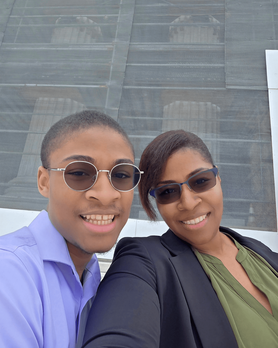 Two people stand in front of the U.S. Supreme Court. The exterior of the Court is partially obscured by scaffolding.