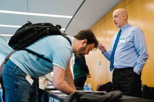 2026-01-16_Pre_Law_Conference_2nd_Annual (21 of 33) A representative speaks with an attendee at an informational table, gesturing while explaining materials during the conference networking session.