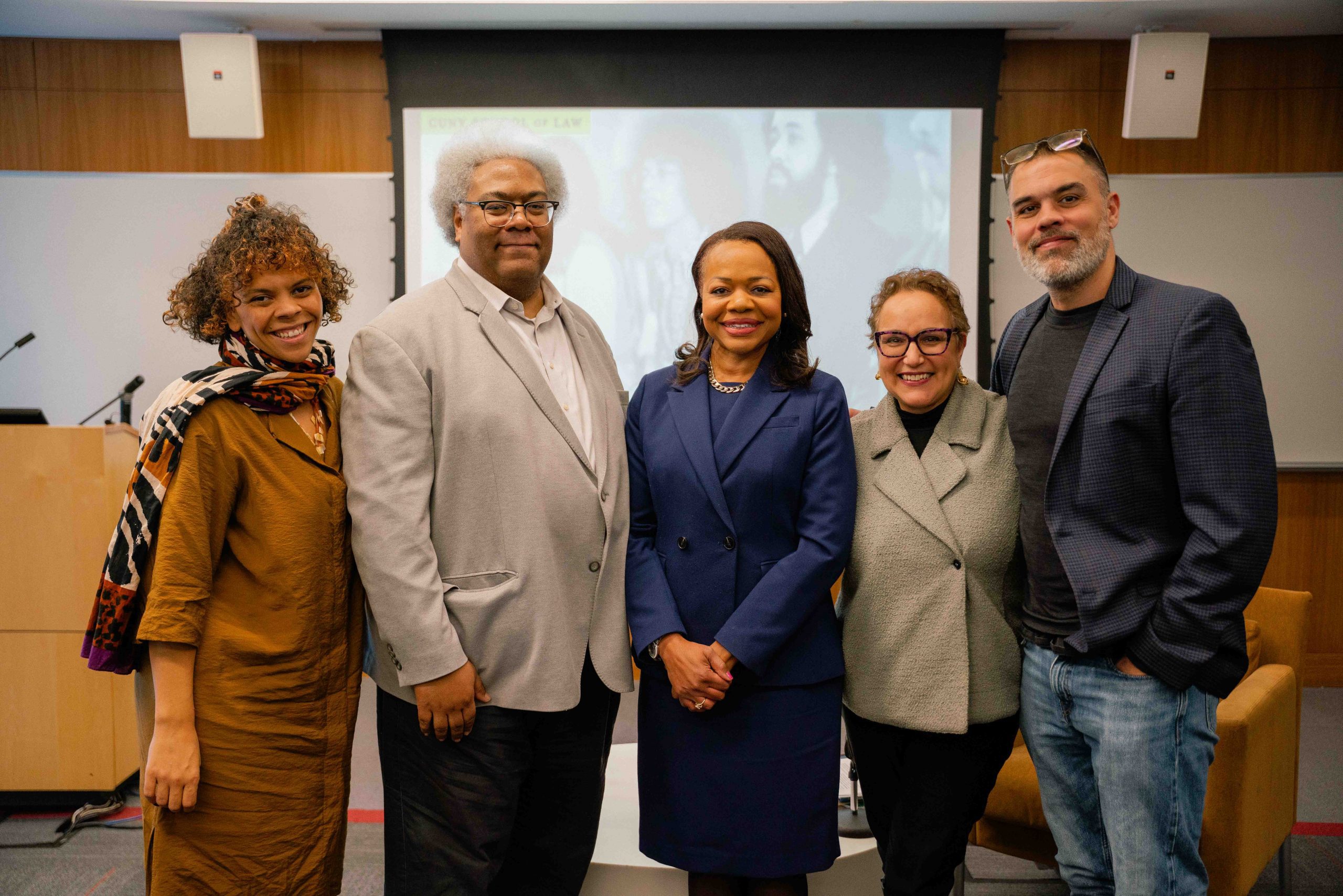 Group photo onstage after the event: Professor Marbré Stahly-Butts, Elie Mystal, Kristen Clarke (2026 W. Haywood Burns Chair), Interim Dean Natalie Gomez-Velez, and Professor John Whitlow pose and smile at CUNY School of Law.