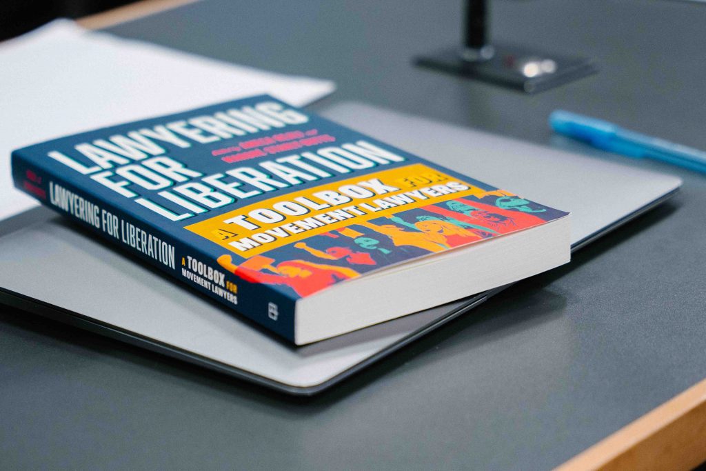 A copy of Lawyering for Liberation: A Toolbox for Movement Lawyers rests on a table during the event.