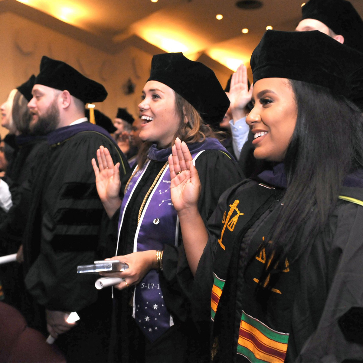 CUNY Law gradates with their right hands raised taking the lawyers pledge.