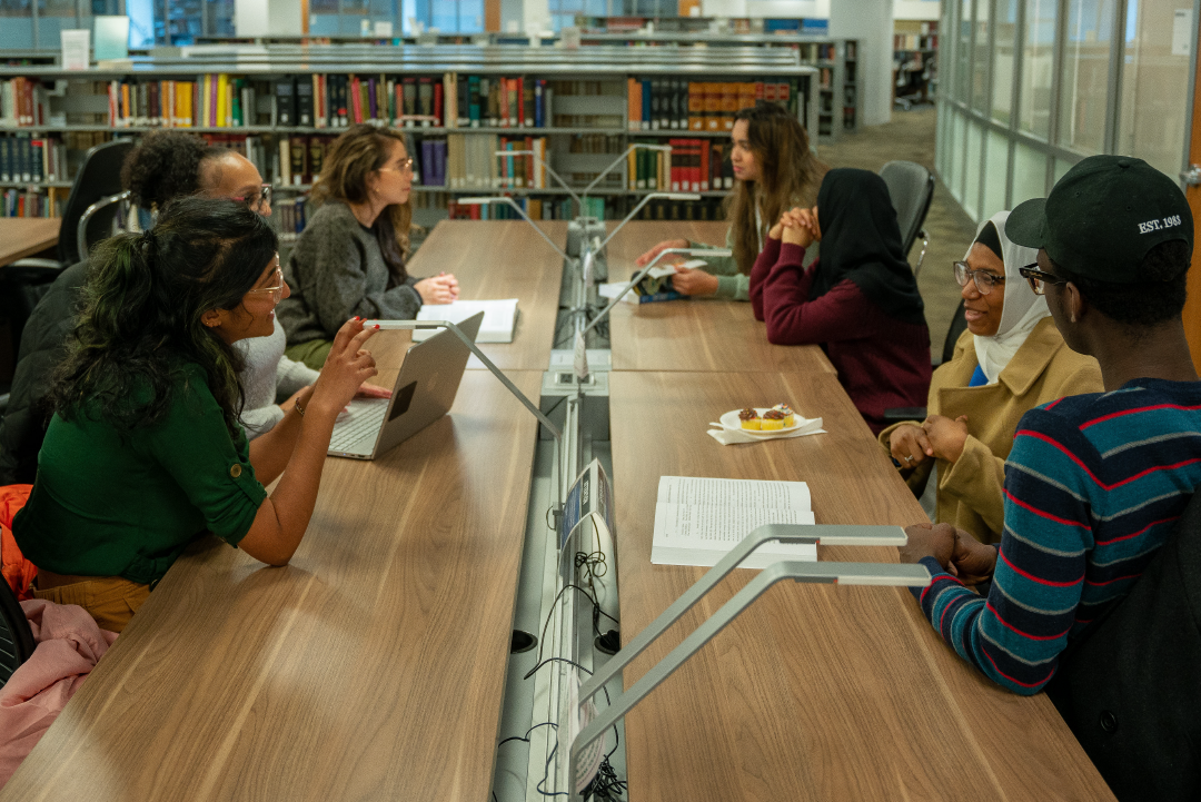 People work and collaborate at a long table in the CUNY Law Library