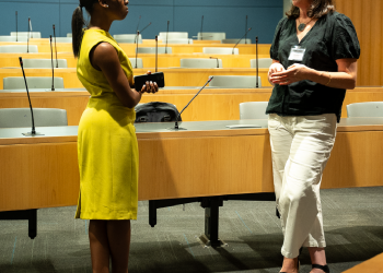 student and professor standing and talking in classroom