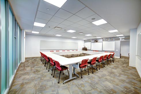 Classroom with table seating arranged in a square with computer podium and digital screen