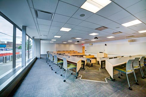 Auditorium tiered style classroom with podium on bottom center row with white board and digital screen