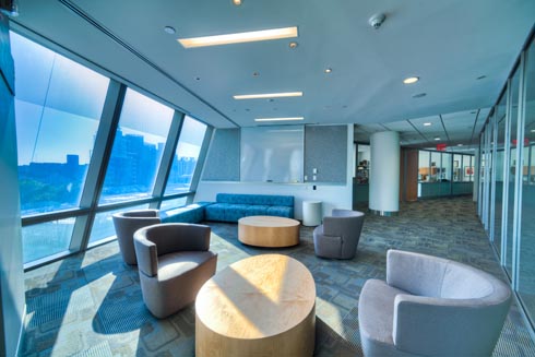 Seating and study area by a wall of windows with a view of Queens and the City