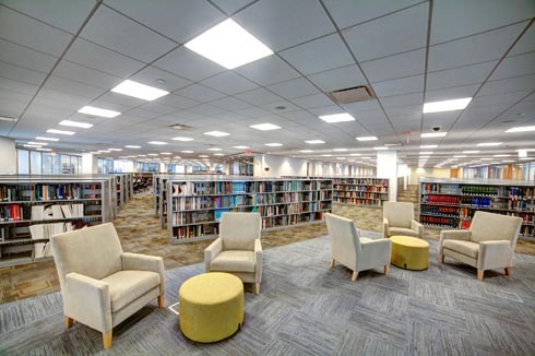 Comfy reading chairs with tables arranged near the book stacks in the library.