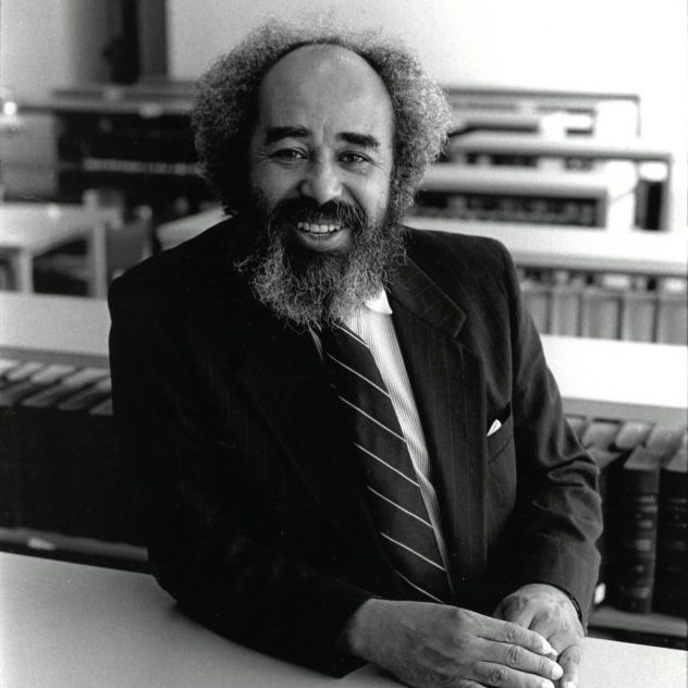 Dean W. Haywood Burns smiles and poses in the CUNY Law library