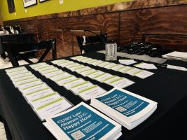 a table with a black tablecloths and rows of CUNY Law nametags. Cards on table promote CUNY Law Alumni DC Happy Hour