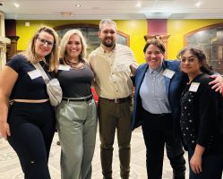 A group of five people posed together facing the camera and smiling Busboys and Poets at the Alumni Happy Hour in DC.