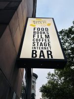A vertical sign outside of Busboys and Poets. The sign reads, "Food, Books, Film, Coffee, Stage, Internet, Bar"