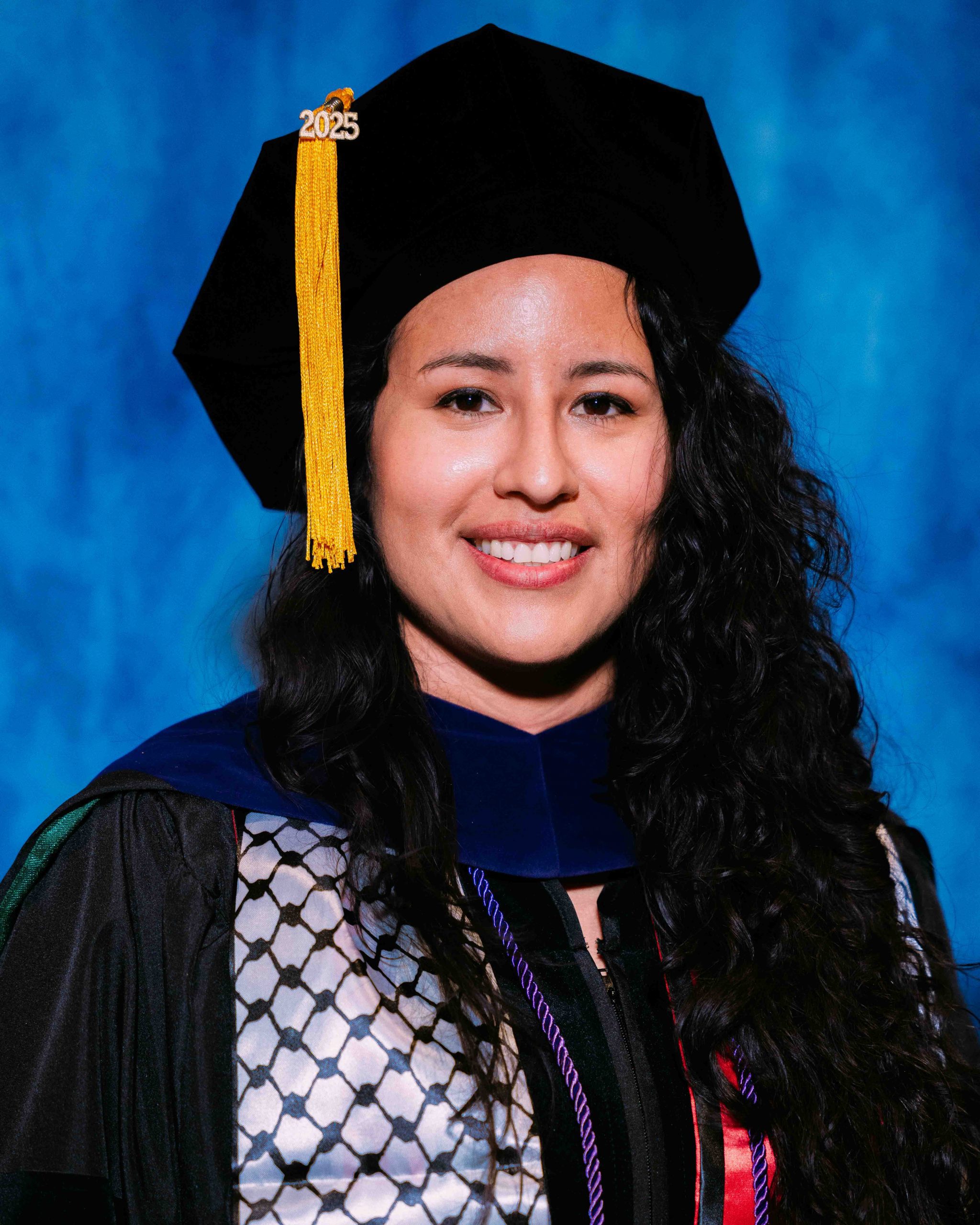 Brenda Valladres poses for a Graduate portrait in graduation regalia.
