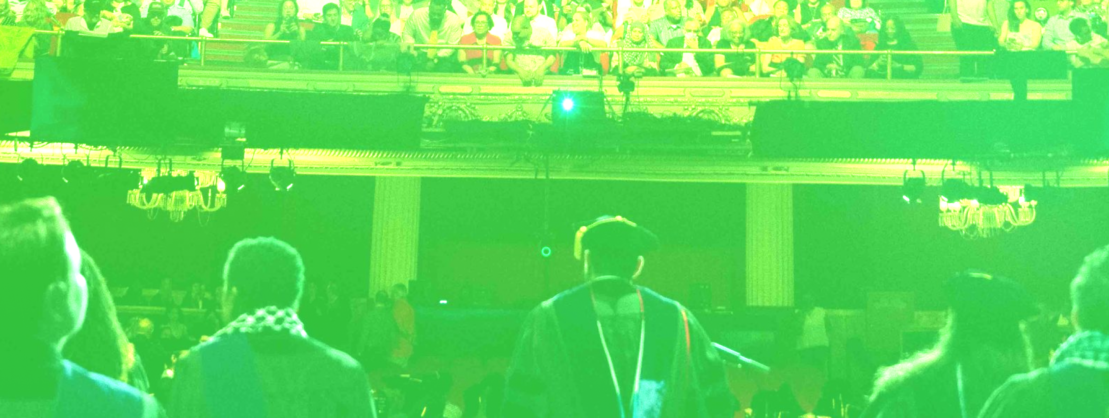 Image of CUNY Law Commencement Speaker addressing crowd of graduates. The image has a lime green filter on top of it.