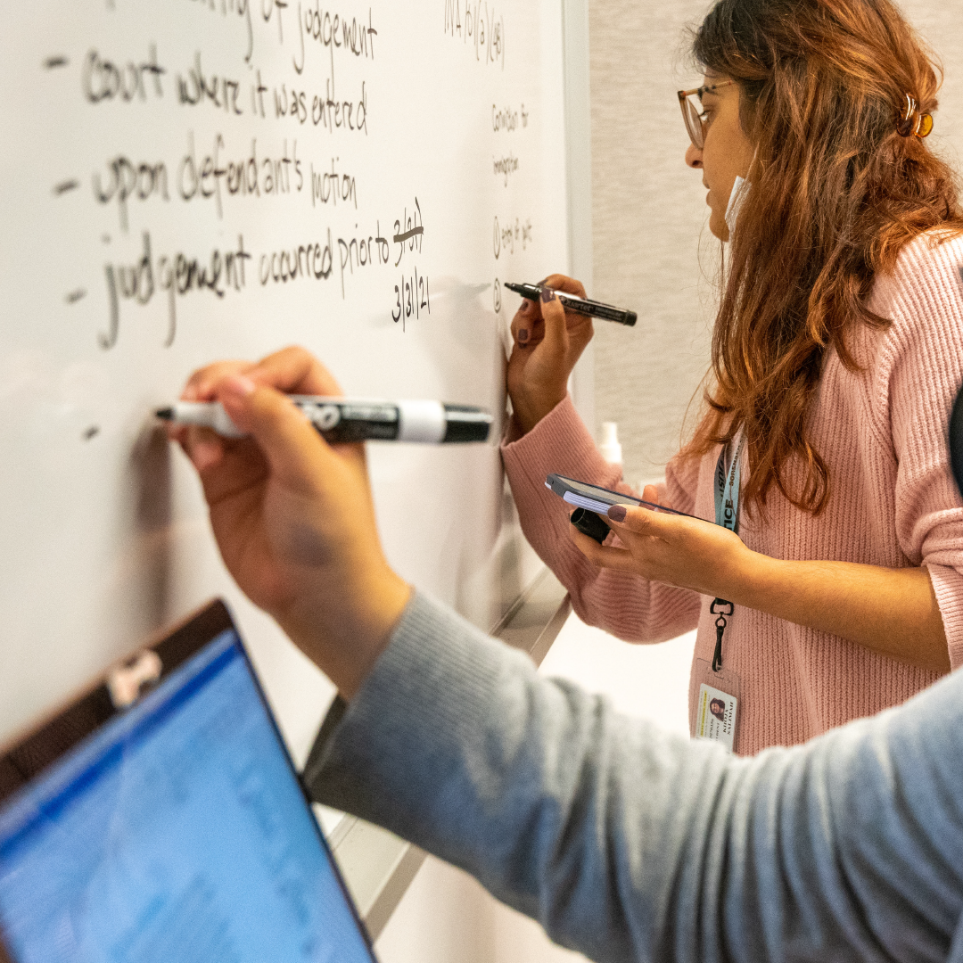 Students write on a whiteboard in a classroom